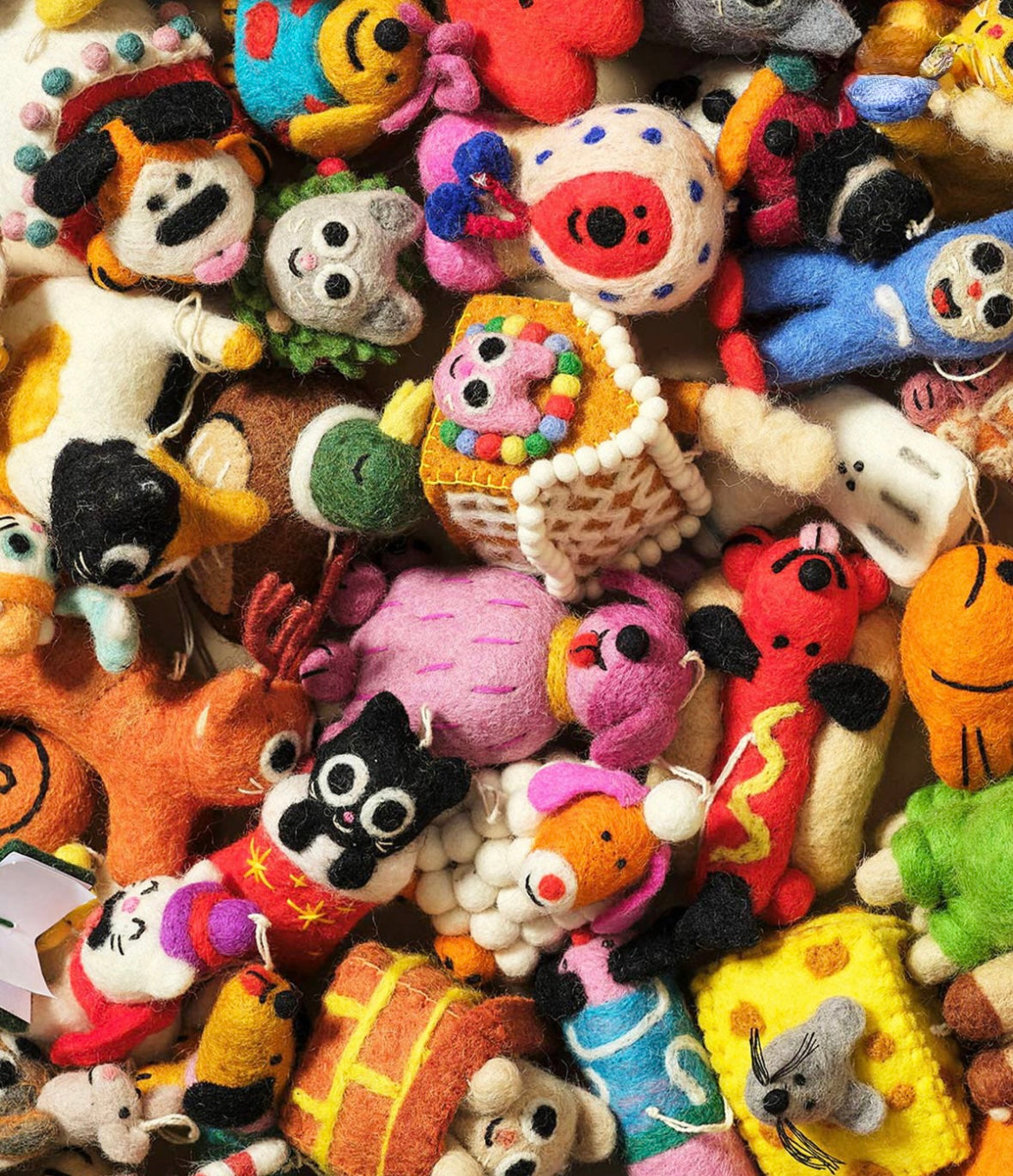 A dense, colorful pile of handmade felt animal toys and small plush characters filling the entire frame.