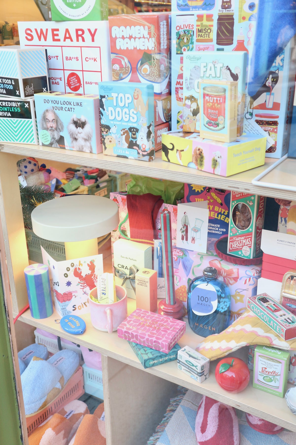 A dense, colorful retail display filled with various miniature toy products, books, and boxes arranged on light wood shelves.