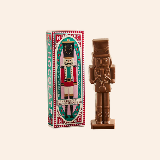 Chocolate nutcracker figurine with packaging on a beige background