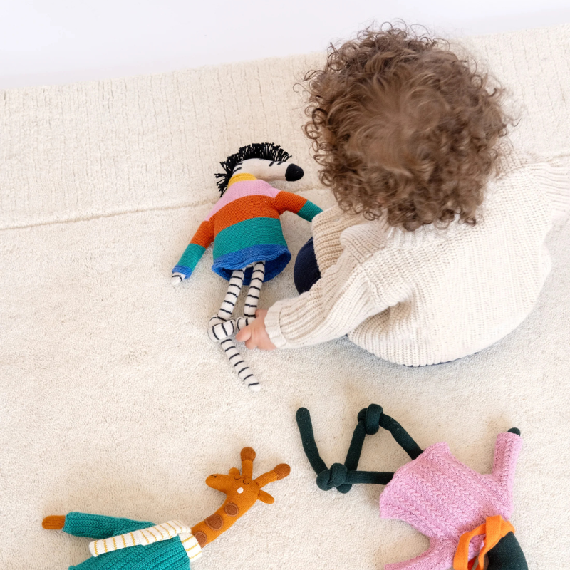 Child playing with colorful knitted dolls on a light surface